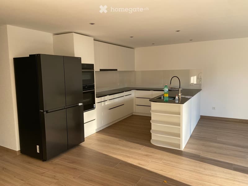 Modern kitchen with white cabinets, black countertops, and a central island. Features a black refrigerator, oven, and a sink with a modern faucet.