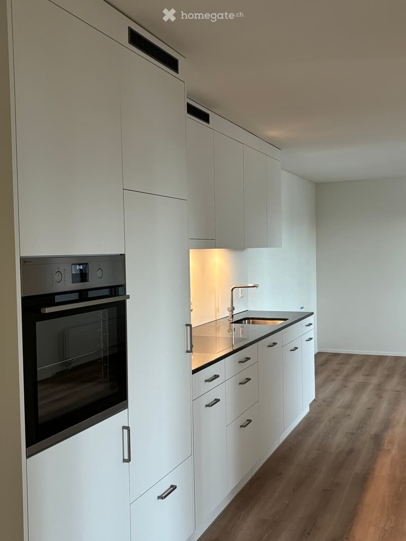 Modern kitchen with white cabinets, a built-in oven, and a sink with a modern faucet.