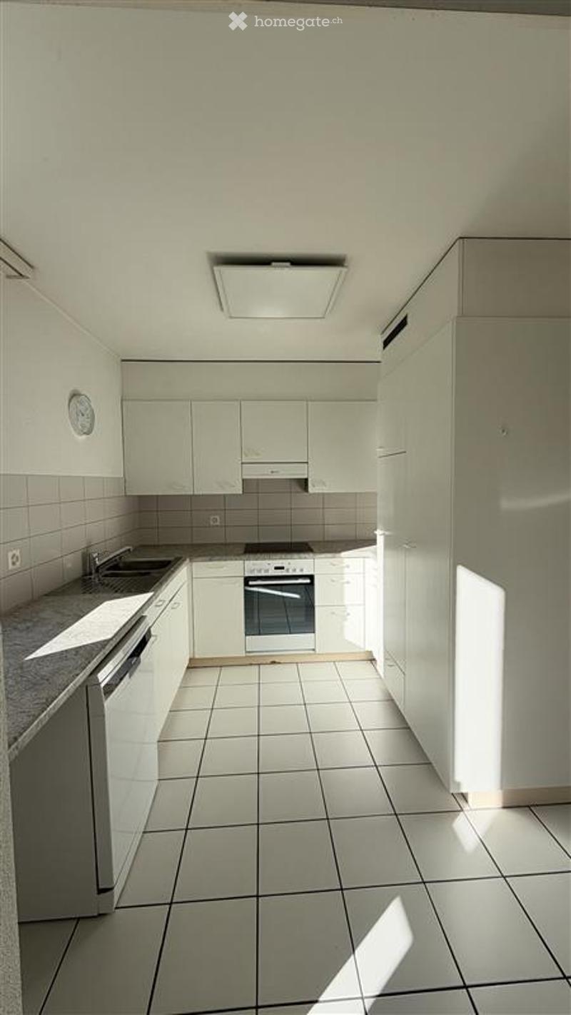 Modern kitchen with white cabinets, tiled floor, and built-in appliances including a sink, oven, and dishwasher.