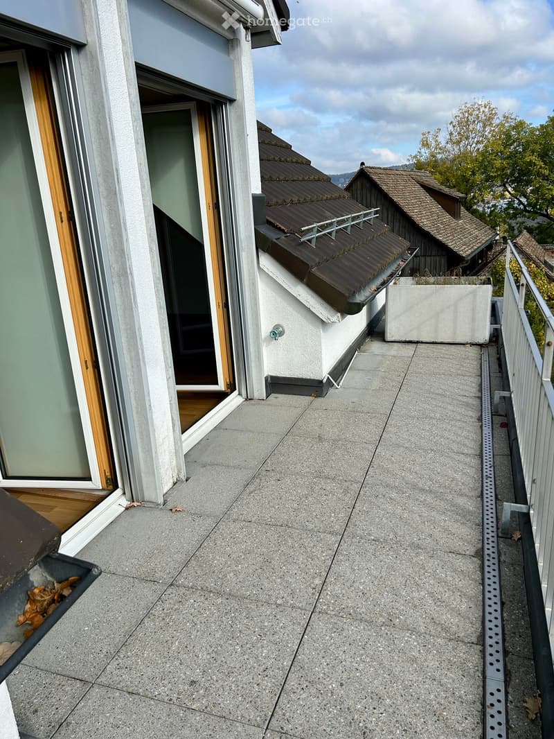 Balcony with concrete floor, metal railing, and open sliding door leading to interior space.