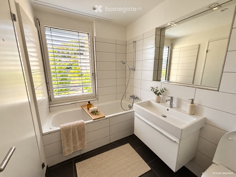 Modern bathroom with a bathtub, sink, large mirror, and a window with blinds. Includes a towel, soap dispenser, and a small plant on the sink.