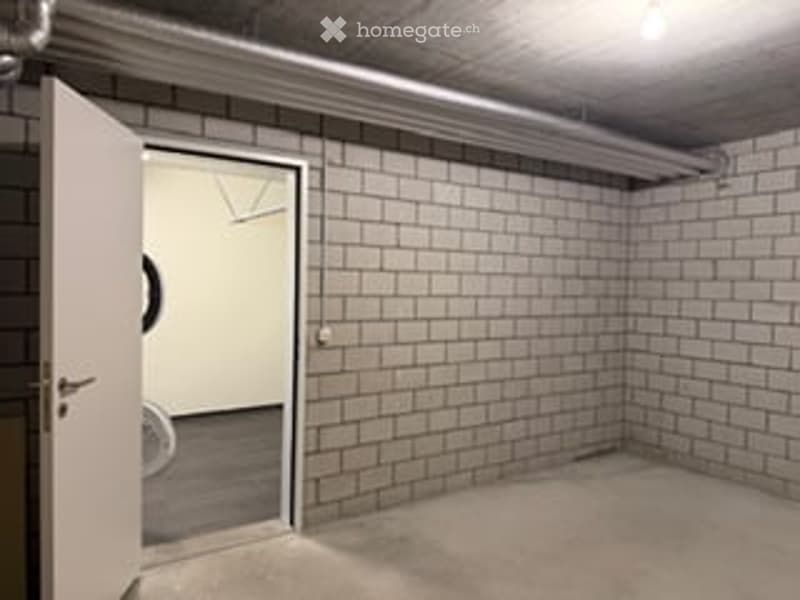 Empty room with exposed brick walls, concrete floor, and a single door leading to another space.
