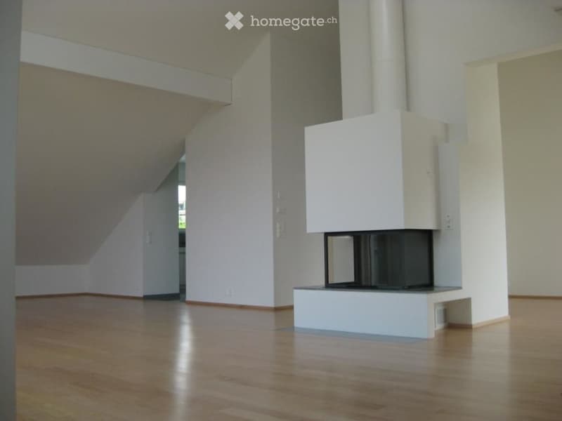 Empty room with wooden flooring and a modern white fireplace, no furniture or equipment present.