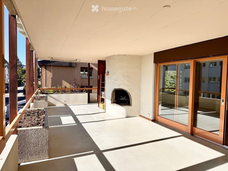 Spacious balcony with a built-in fireplace, large sliding glass doors, and a view of the surrounding area.