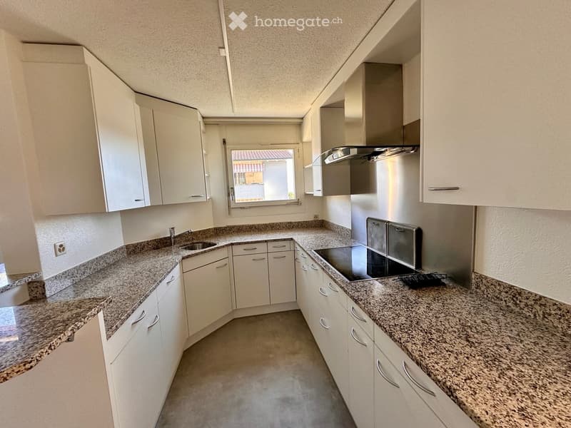 Modern kitchen with white cabinets, granite countertops, stainless steel appliances, and a window overlooking the exterior.