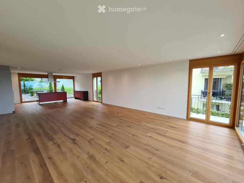Empty room with wooden flooring, white walls, and large sliding glass doors leading to a balcony area.