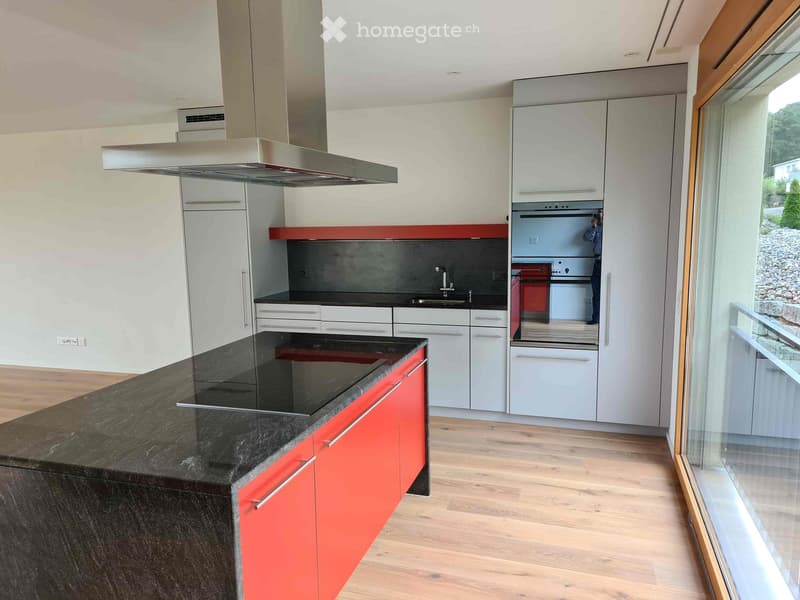 Modern kitchen with white and red cabinets, black granite island, induction cooktop, and stainless steel range hood.