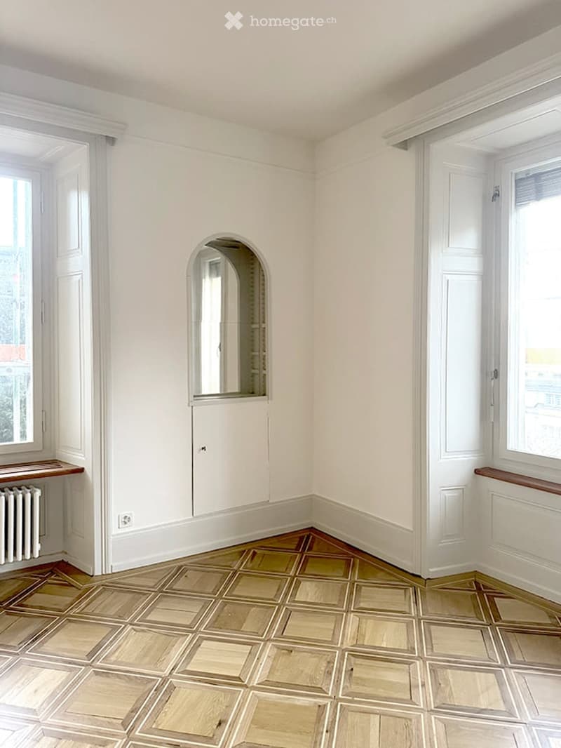 Empty room with white walls, large windows, and a decorative tiled floor. No furniture or equipment is present.