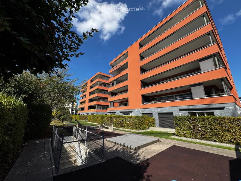 Modern orange apartment building with multiple balconies and a landscaped courtyard area.