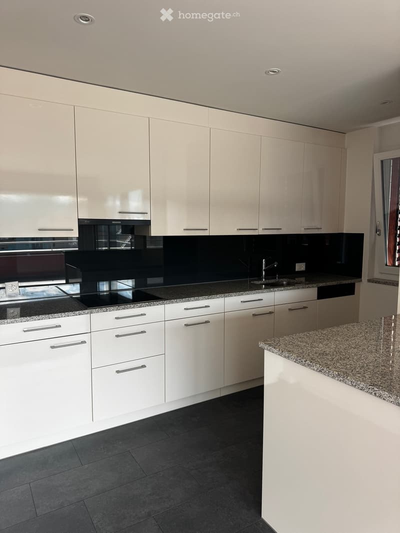 Modern kitchen with white cabinets, granite countertops, and stainless steel appliances.