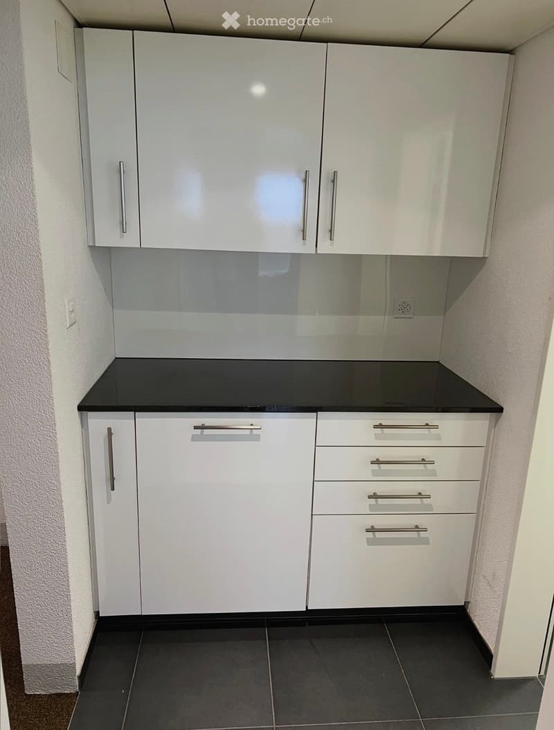 Modern kitchen with white cabinets, black countertop, and black tiled floor.