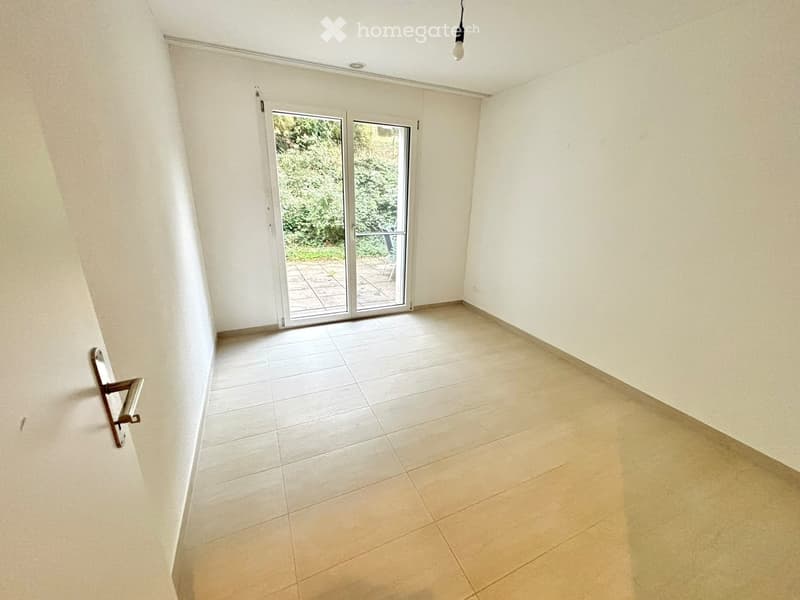Empty room with tiled floor, white walls, and a sliding glass door leading to an outdoor area.