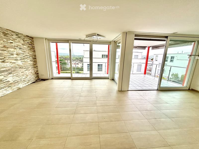 Empty room with tiled floor, large sliding glass doors leading to a balcony, and a textured stone accent wall.
