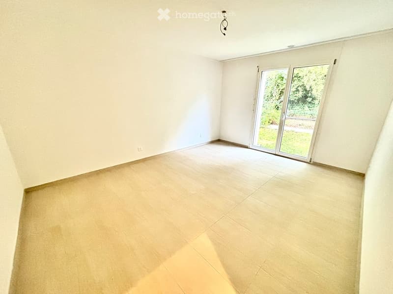 Empty room with light-colored tiled flooring and white walls, featuring a large sliding glass door leading to an outdoor area.