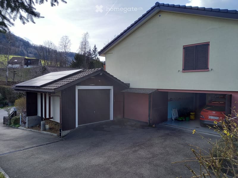Two-story house with a garage, solar panels on the roof, and a scenic mountain view in the background.