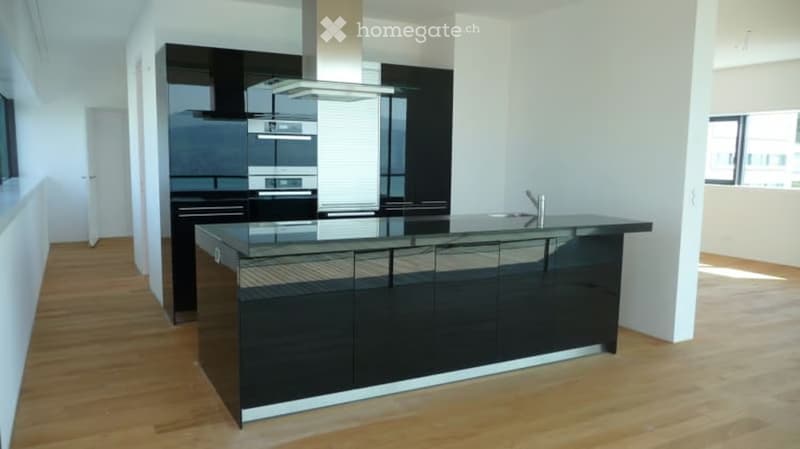 Modern kitchen with black cabinets, a central island, and stainless steel appliances, including an oven and a faucet.