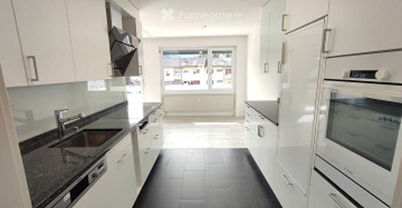 Modern kitchen with white cabinets, black tiled floor, granite countertop, stainless steel sink and faucet, and built-in oven.