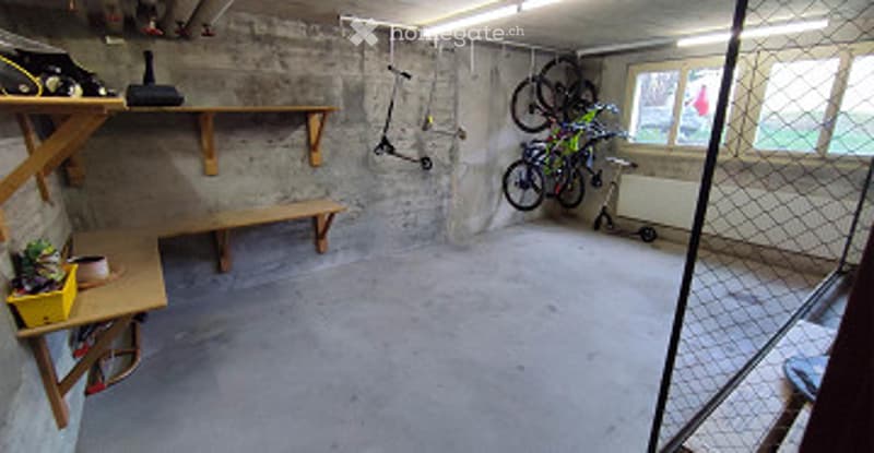 Empty garage with concrete floor, wooden shelves, and a small bench. No furniture or equipment.