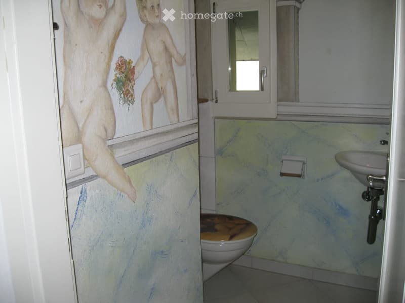 Bathroom with a painted mural on the wall, a toilet, a sink, and a mirror above the sink.