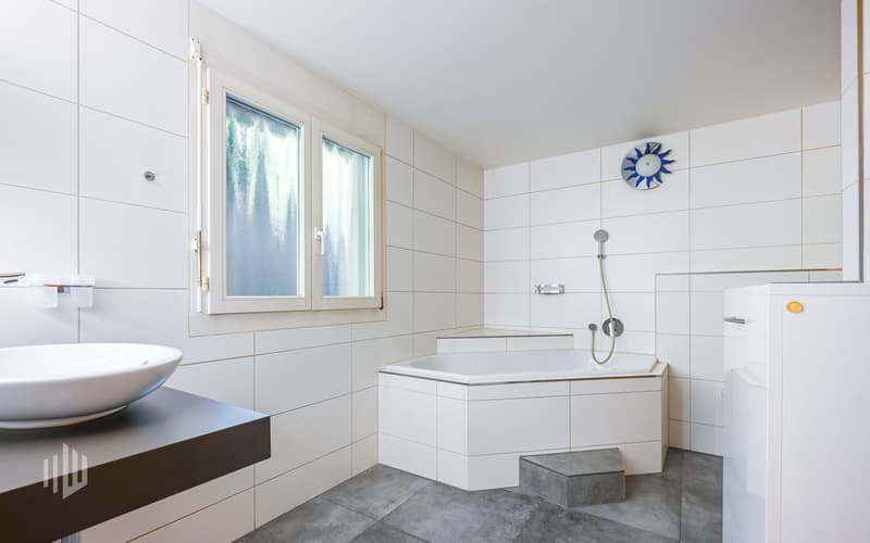 Badezimmer mit Badewanne, Toilette und Kombigerät Waschmaschine/Tumbler