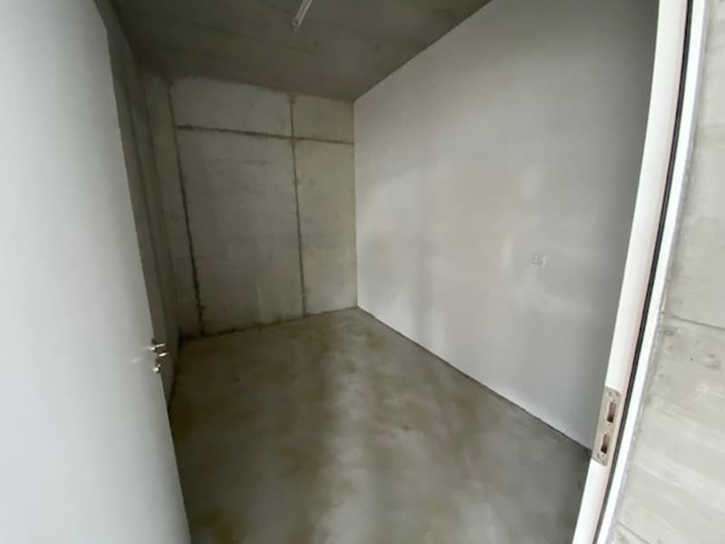 unfurnished room with white walls, concrete floor, open door