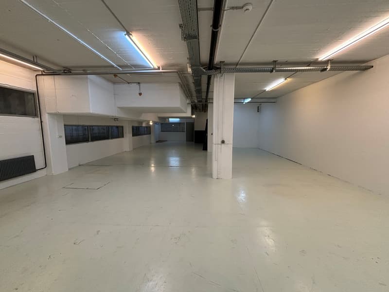 Empty room with white walls, ceiling, and flooring, no furniture, windows and pipes on walls