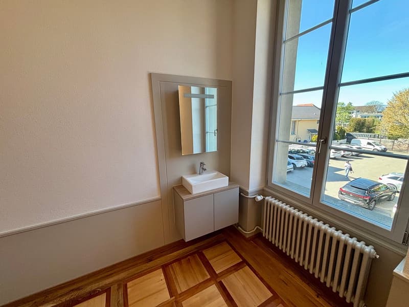 Bathroom with white sink, mirror, wooden floor, radiator, large window