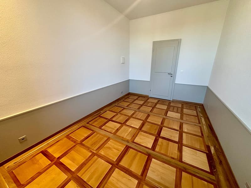 empty room, wooden parquet floor, white walls, door, power outlet