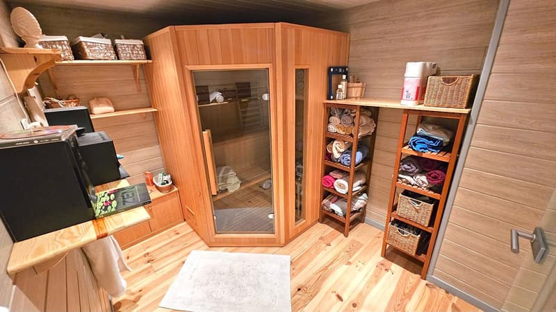 sauna room with wooden benches, shelves with towels, a sauna cabin