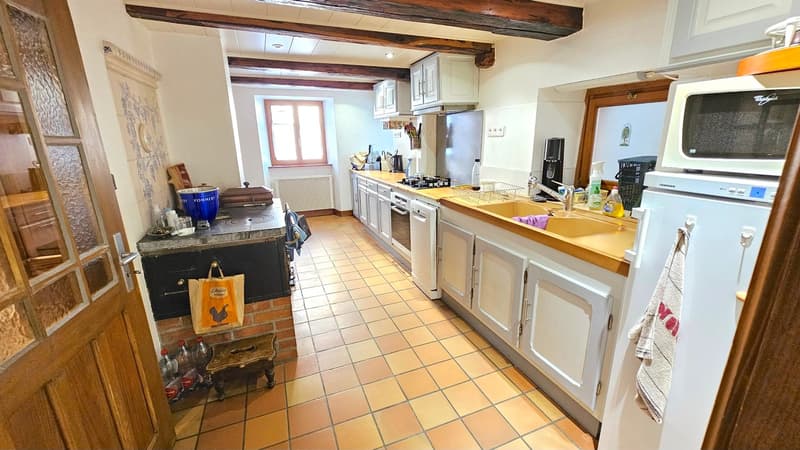 Kitchen with white cabinets, gas stove, sink, refrigerator, dishwasher, microwave, wine rack, wooden floor, window, wooden ceiling beams