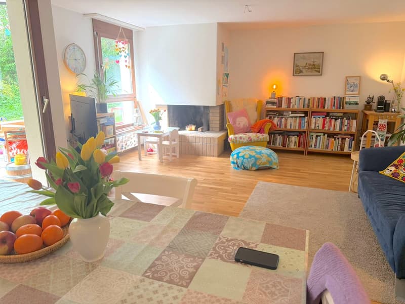 wooden floor, fireplace, bookshelves, armchair, sofa, dining table with flowers, TV, clock