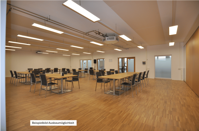 large hall, wood floors, fluorescent lights, long tables and chairs, open doors, projector, speaker