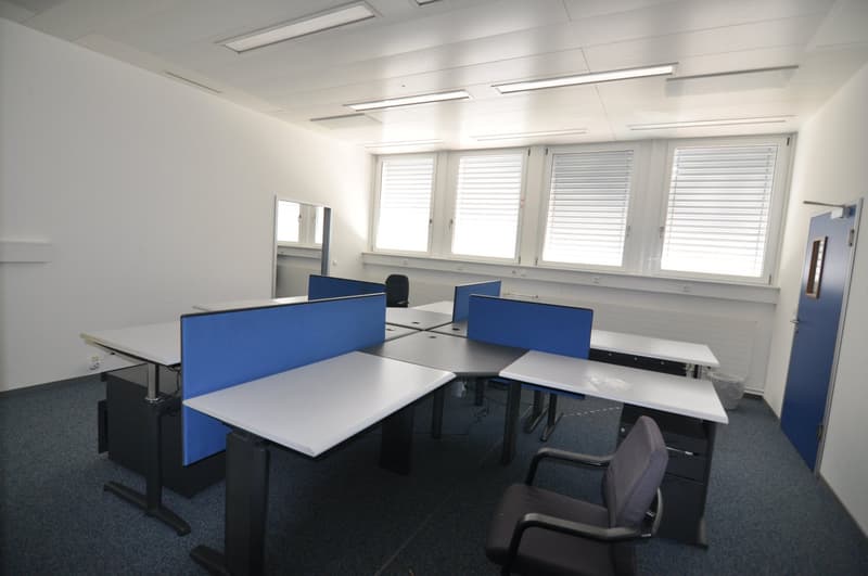 Office setup with several desks, cubicles, chairs, mirrors, and windows