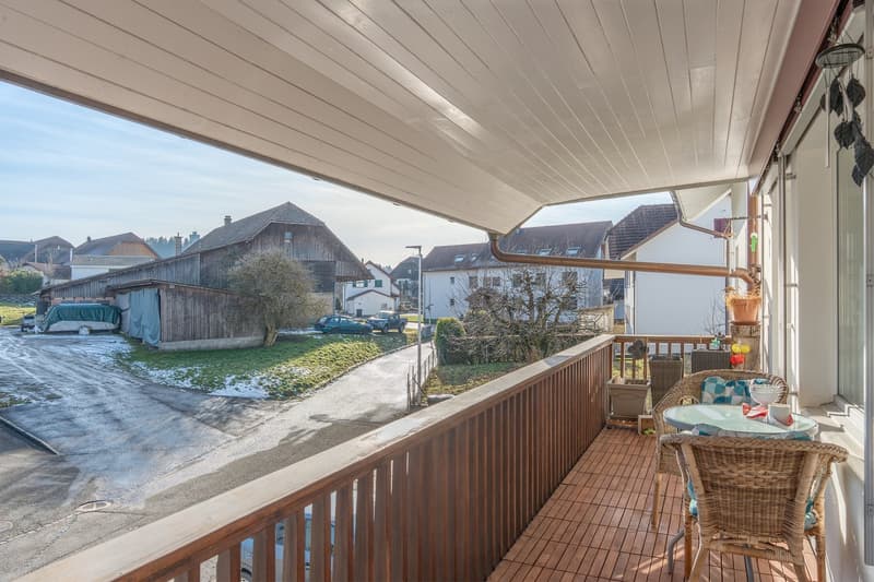 wooden floor, railings, table, chairs, cars parked in background