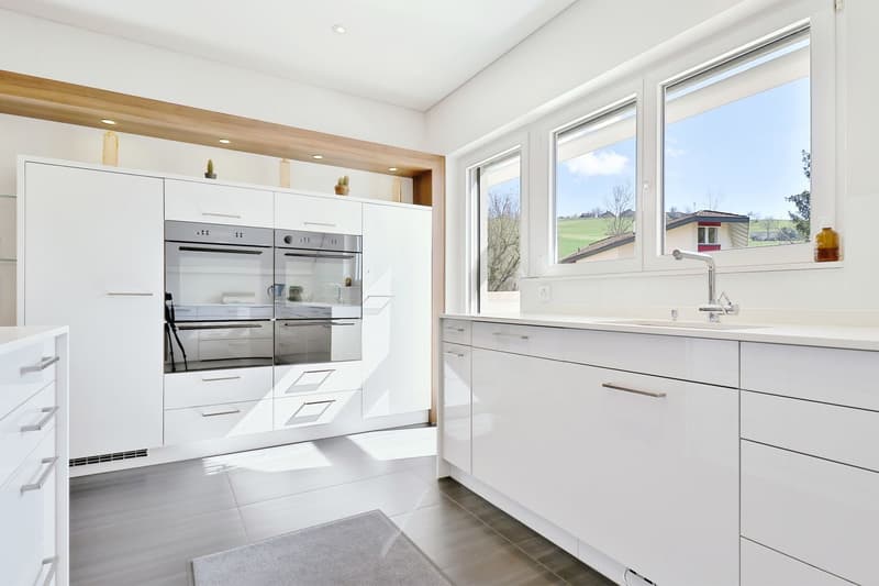 modern kitchen, white cabinets, white drawers, stainless steel appliances, gray tile flooring, double oven, large windows, view of countryside