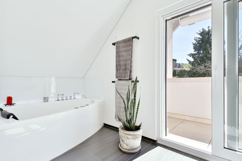 white bathtub, white ceramic sink, grey tiles, open door to balcony
