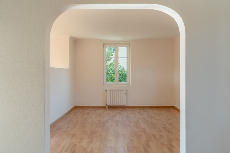 empty room, wooden floor, white walls, arched entrance, window with white frame, white radiator