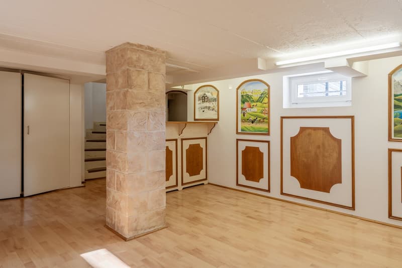 wooden floor, white walls, wooden cabinets, central pillar, paintings, window, stairs