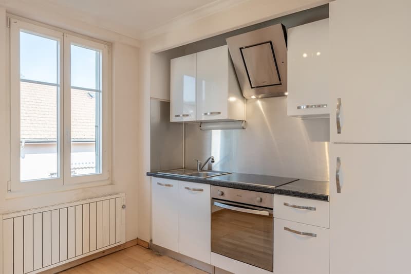 modern kitchen with white cabinets, stainless steel appliances, wooden floor, large window