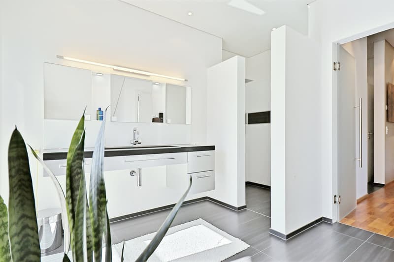 minimalistic bathroom with white wall, black sink, stainless steel faucet, and white tile flooring