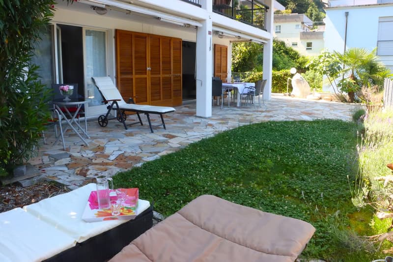 Stone patio with seating, large windows, open balcony, wooden doors