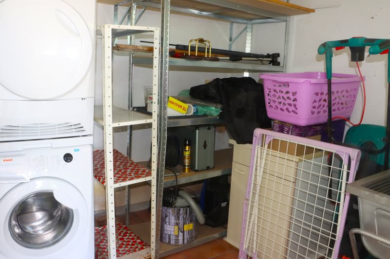 Storage room with shelves, table, washing machine, and vacuum cleaner