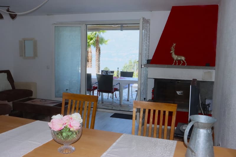 open to dining area, fireplace, dining table with flowers, living couch, TV, glass doors