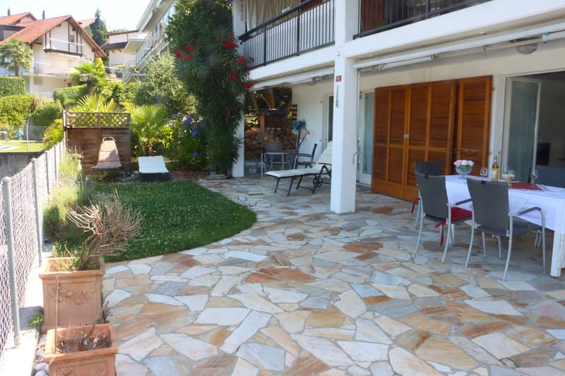 Flagstone patio with lounge chairs, table with wine bottles and glasses, plants, and shrubs