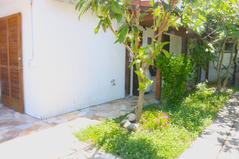 white building, wooden door, stone pathway, plants, flowers