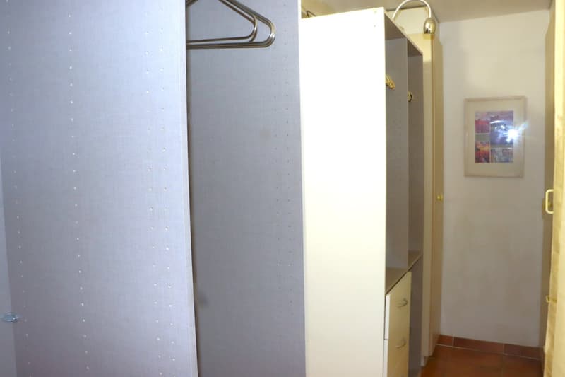 large wardrobe with many compartments and drawers, metal hangers, light in the closet, empty room