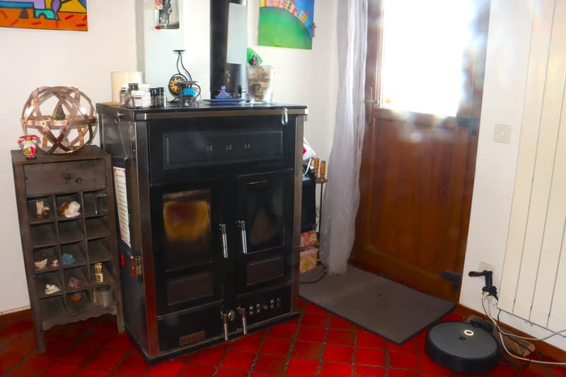 black wood burning stove, shelves with objects, red floor