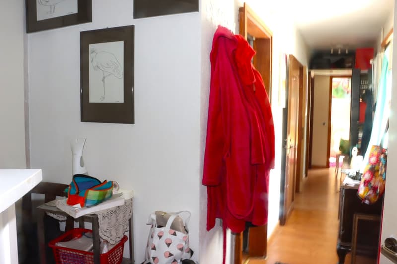Corridor with a table, a red basket, and a pink jacket hanging on a hook.