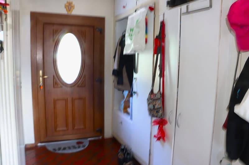 hallway with wooden door, white cabinets, clothing hanging, mat by the door