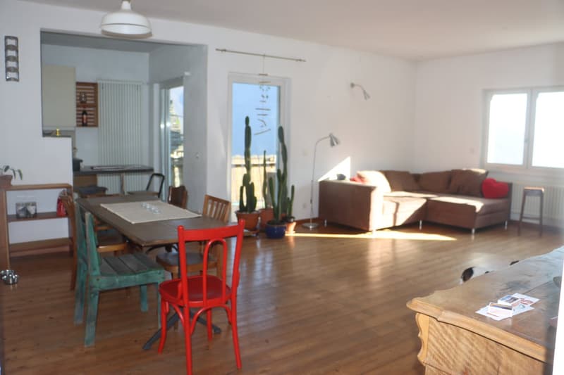 Dining area with wooden floor, dining table, chairs, couch, lamps, potted plants, and a view of the outside